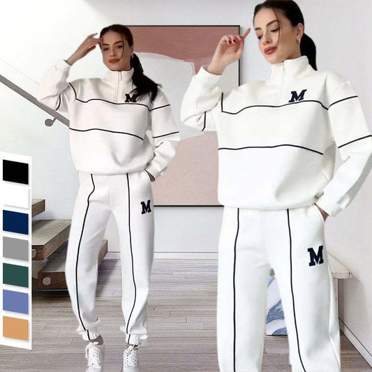 White tracksuit with black piping and 'M' logo, paired with sneakers